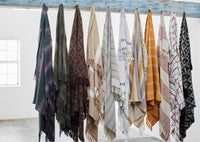 Row of patterned throws hanging in a studio setting showing varied textures and colours