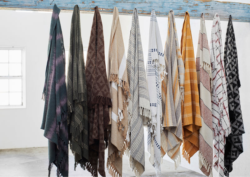Row of patterned throws hanging in a studio setting showing varied textures and colours