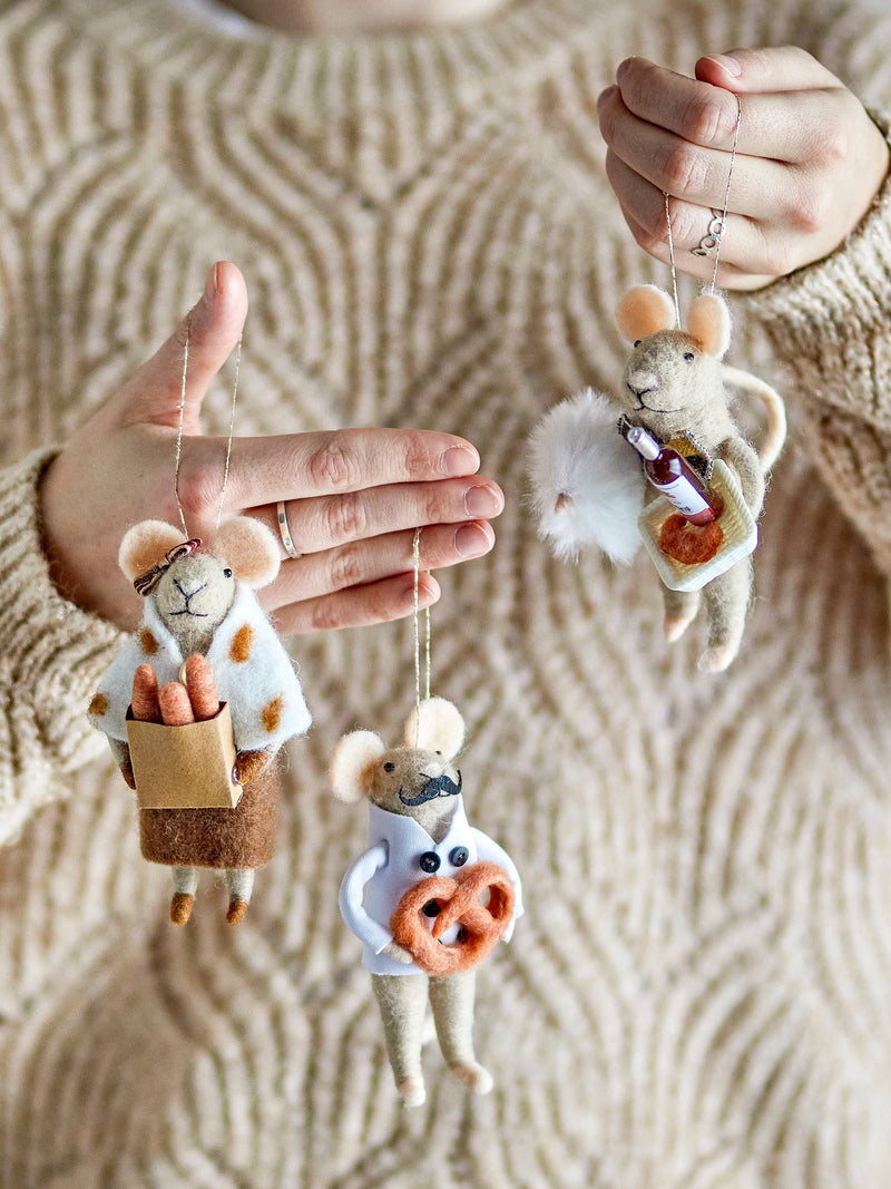Close-up of hands holding three wool mice Christmas ornaments with baking accessories