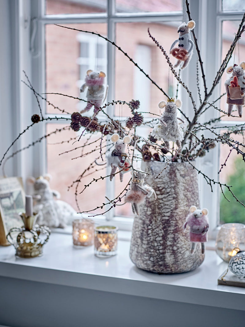 Felt mice Christmas ornaments hanging from winter branches in a vase with candles on windowsill