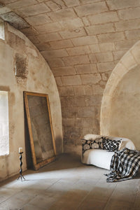 Phoenix cushion by Olsson & Jensen on a sofa in a stone-walled room
