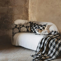 Phoenix cushion by Olsson & Jensen styled on a white sofa with a checked throw