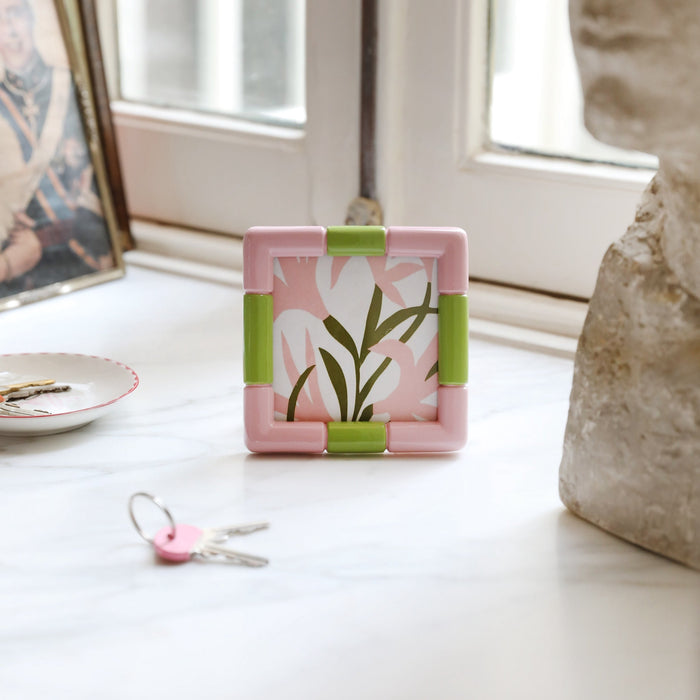 Playful pink photo frame bringing pop-colour charm to a bright windowsill.
