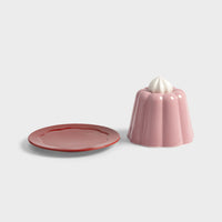 Pink pudding cloche lid lifted off its red serving plate by &Klevering