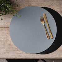 Aida Quadro reversible placemat in black and grey with gold cutlery on wooden table

