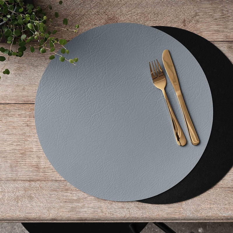 Aida Quadro reversible placemat in black and grey with gold cutlery on wooden table
