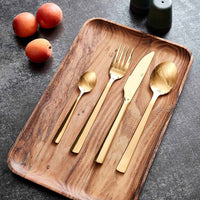 Gold cutlery set on a wooden tray with peaches and scandi salt and pepper shakers in the background