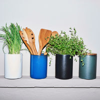 RAW northern green canister with teak lid by aida styled with kitchen accessories on a shelf

