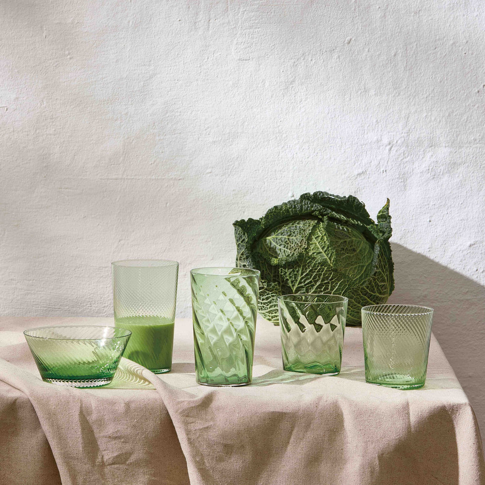 Elegant handcrafted green drinking glasses from Aida RAW styled on a table with a cabage