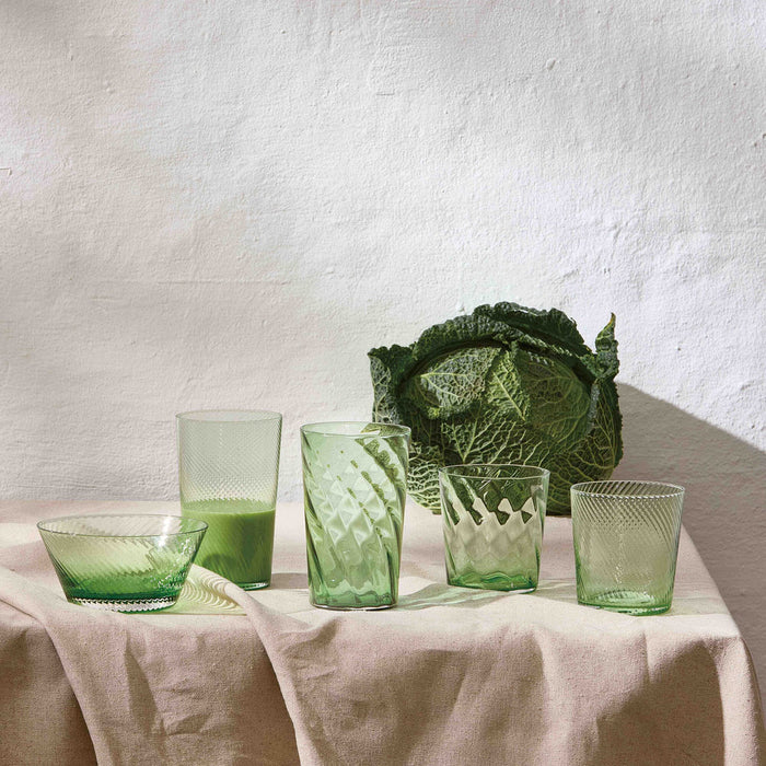 Elegant handcrafted green drinking glasses from Aida RAW styled on a table with a cabage