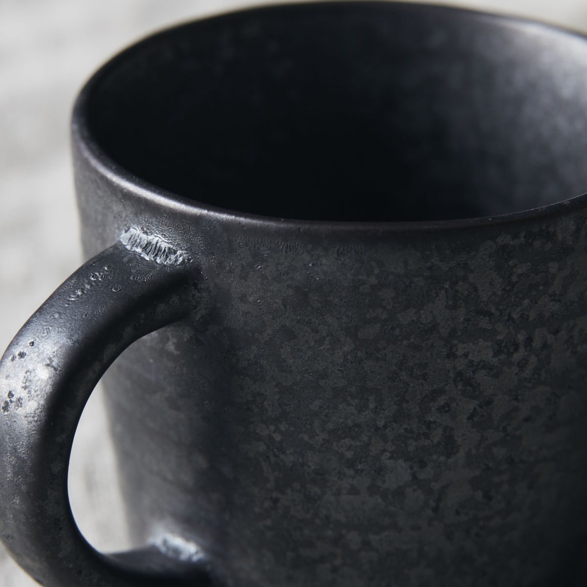 Close up of handle of black and brown stoneware cup for elevating daily coffee moments