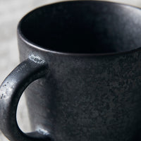 Close up of handle of black and brown stoneware cup for elevating daily coffee moments