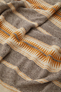 Recycled cotton throw in ecru, brown and honey tones shown close-up with textured weave