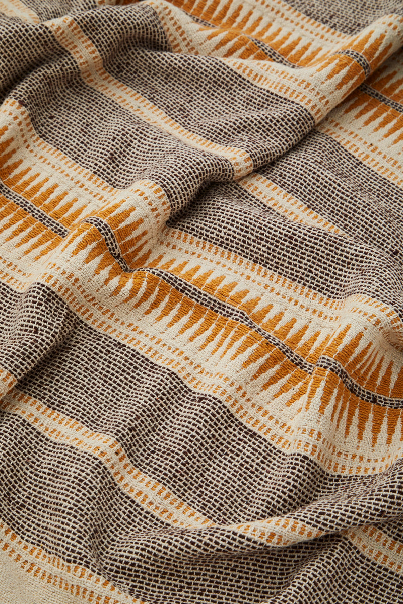 Recycled cotton throw in ecru, brown and honey tones shown close-up with textured weave