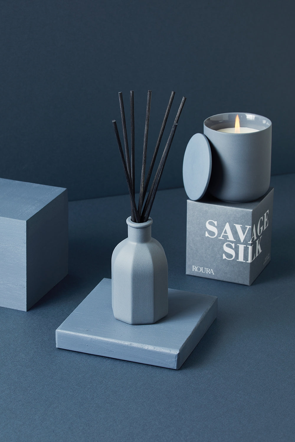 Savage Silk ceramic candle with matching box and reed diffuser in deep blue tones
