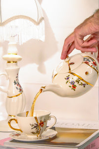 Seletti Kintsugi teapot pouring tea into matching gold-detailed cup and saucer
