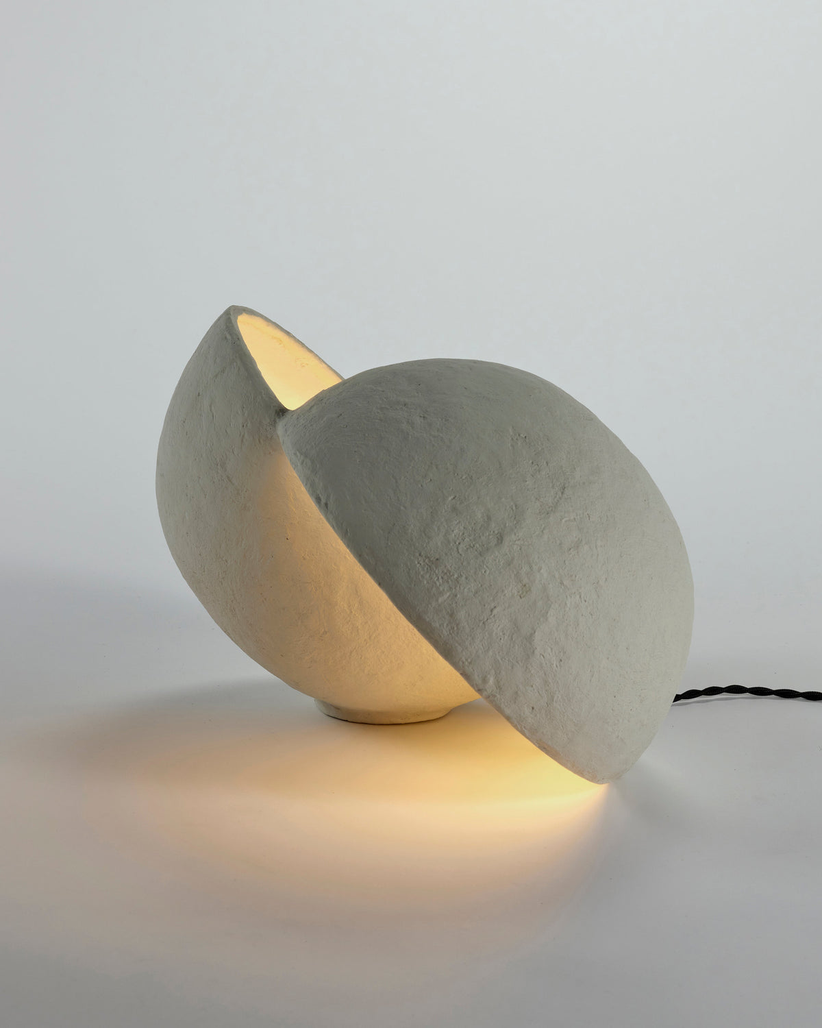 Serax Earth paper mâché table lamp lit, showing the opening between the two halves
