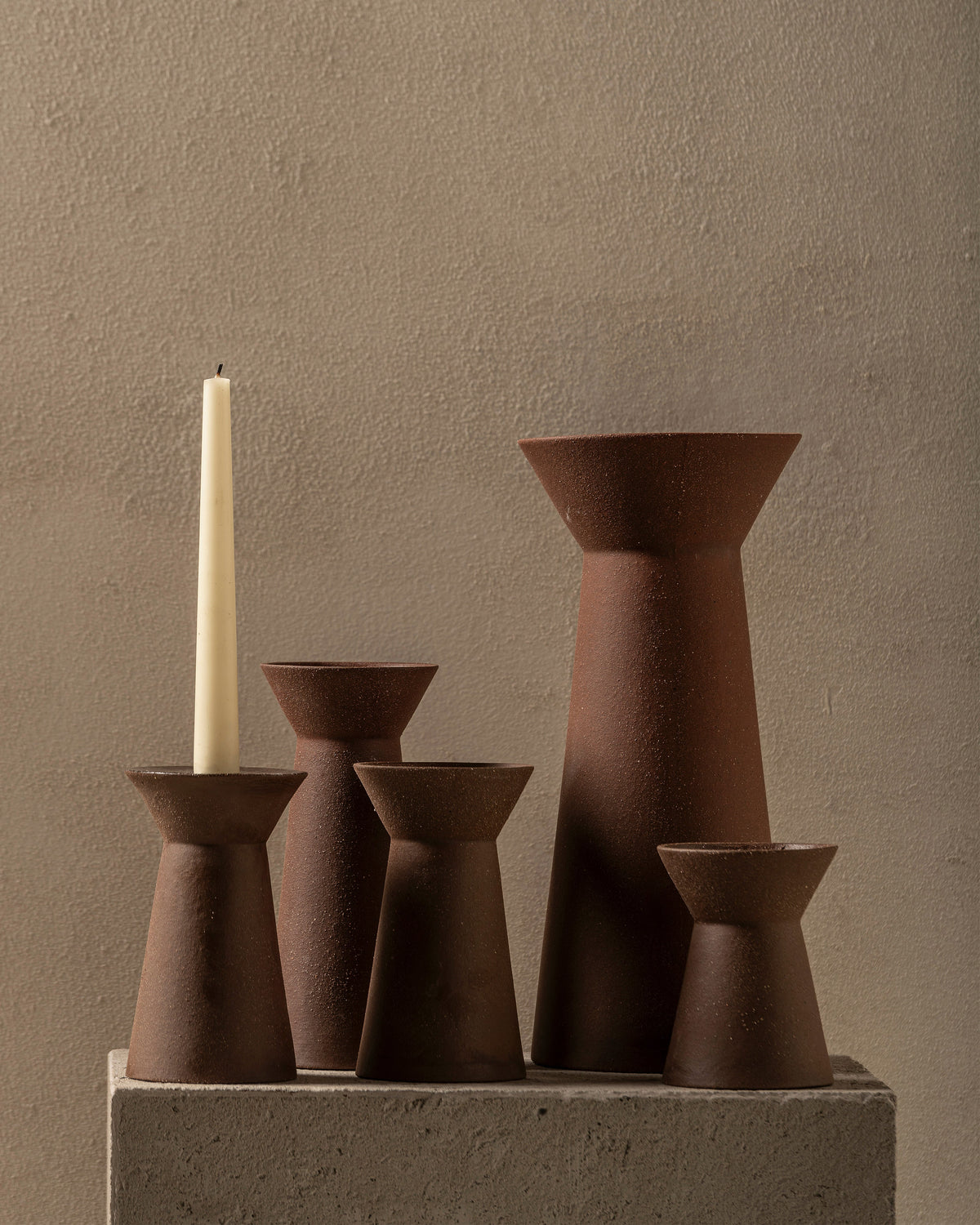 Serax Marie-Ann candle holders and vases grouped on a stone plinth with a dinner candle