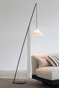 Seam porcelain floor lamp by Serax arching over a cream sofa in a minimalist living room