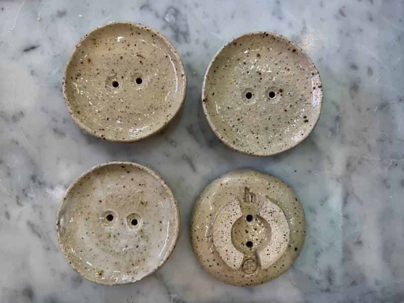 four ceramic soap dishes showing the makers mark and handmade details