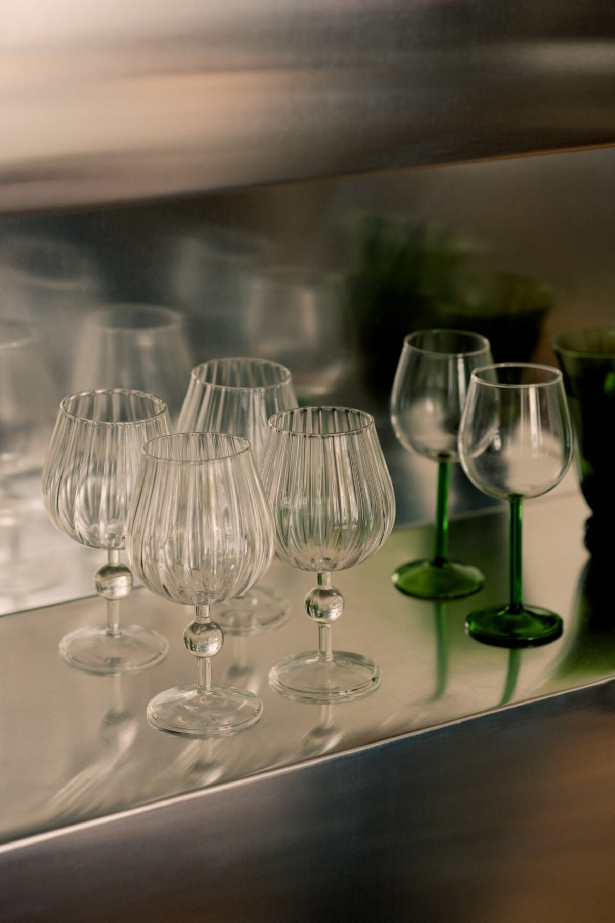 Skye wine glasses by Olsson & Jensen lined up on a mirrored shelf