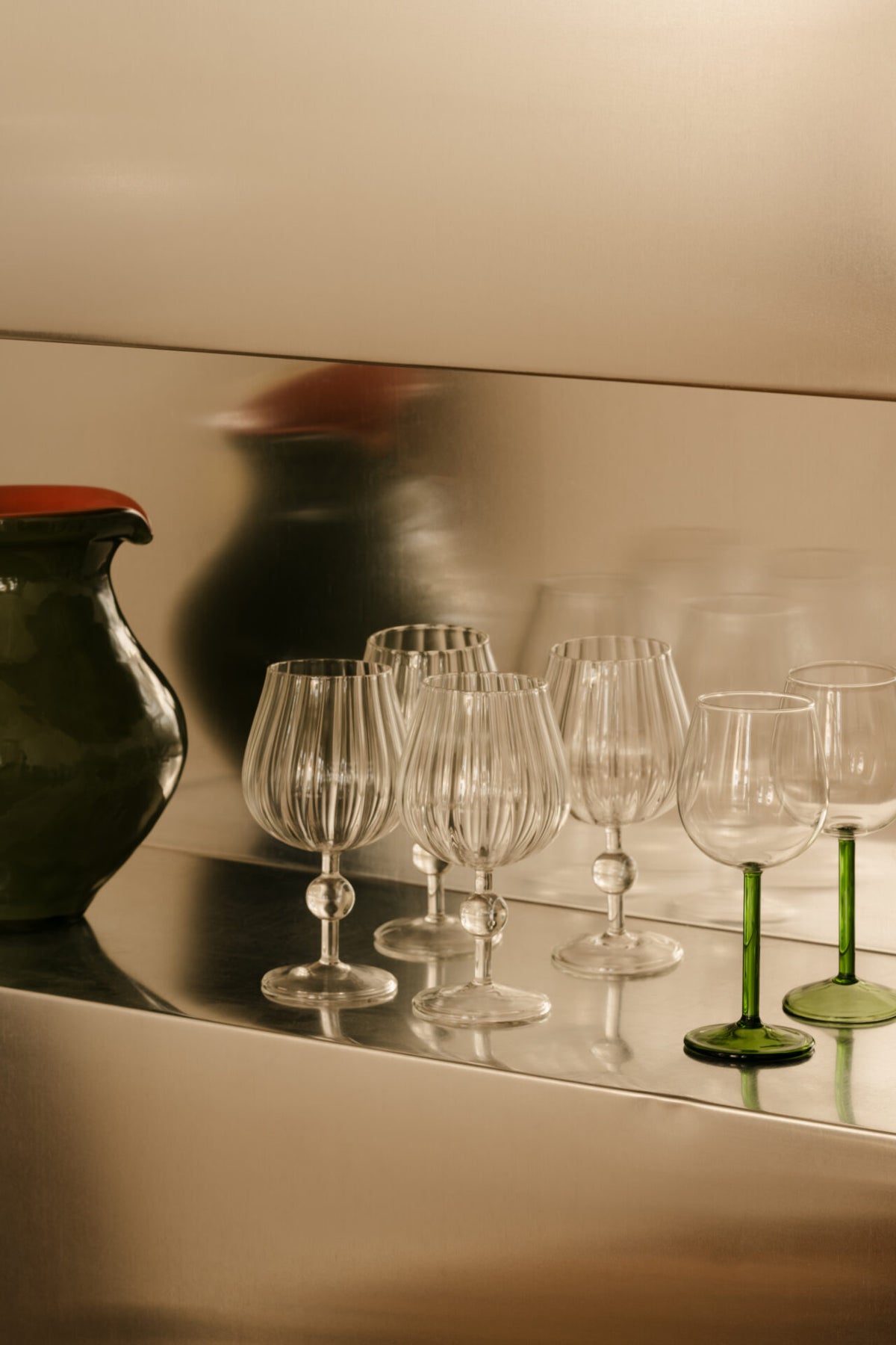 Skye wine glasses by Olsson & Jensen beside a green glass jug on a shelf