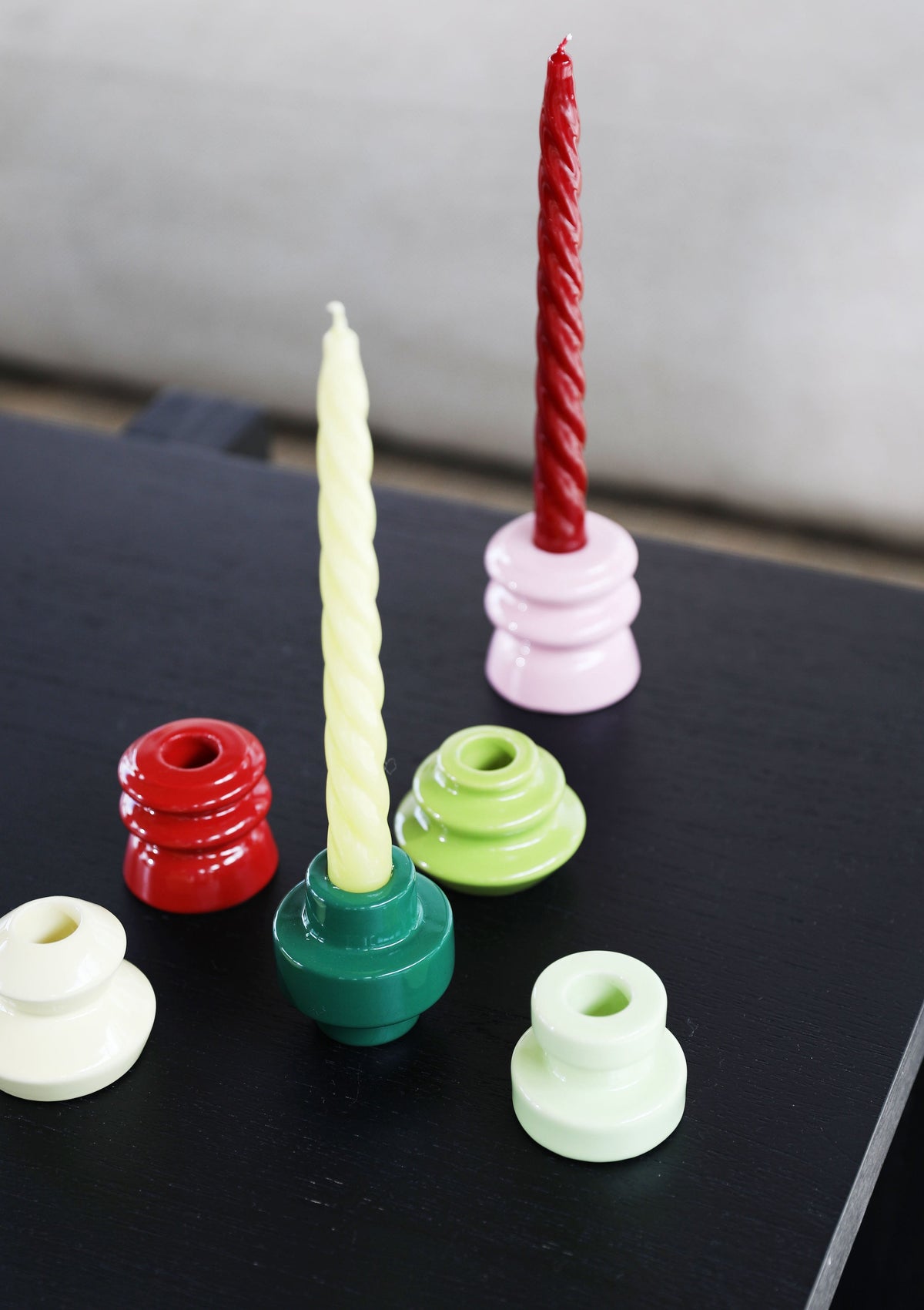 Colourful &Klevering candle holders with twisted taper candles on a black table