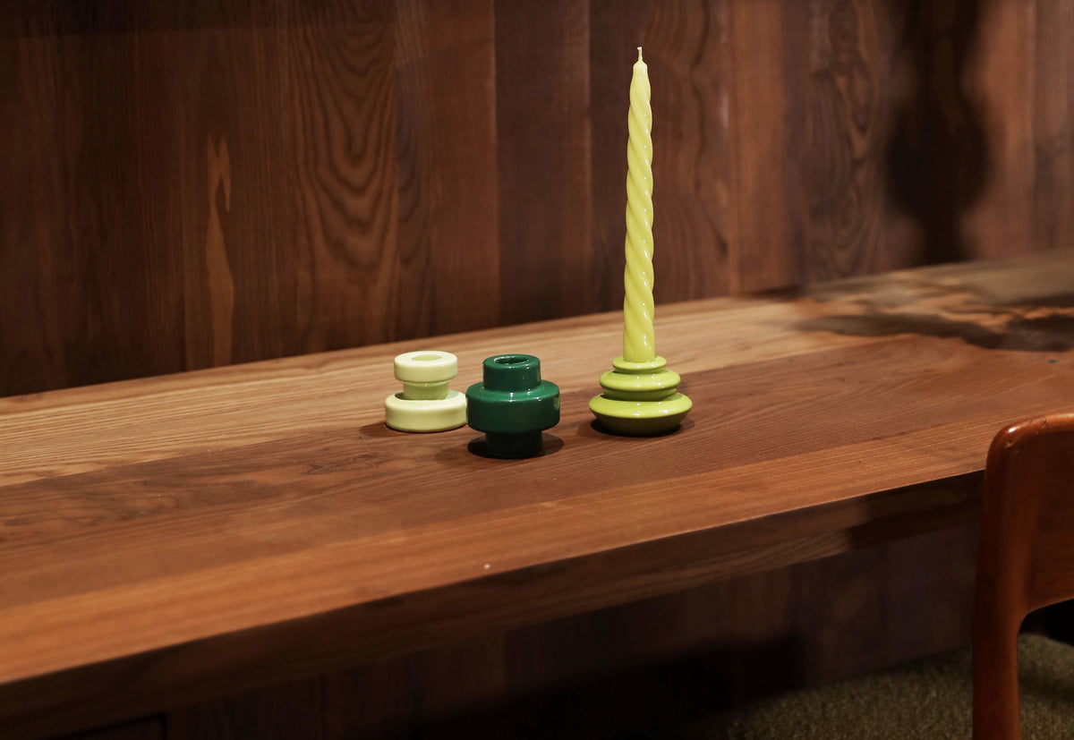 Green candle holders with a twisted taper candle on a long walnut desk