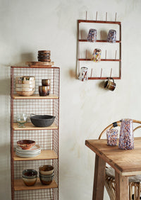 coloured drinking glasses displayed on a wall rack in a relaxed kitchen setting
