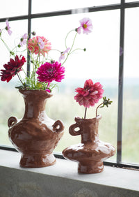 brown stoneware vases styled with colourful flowers on a windowsill
