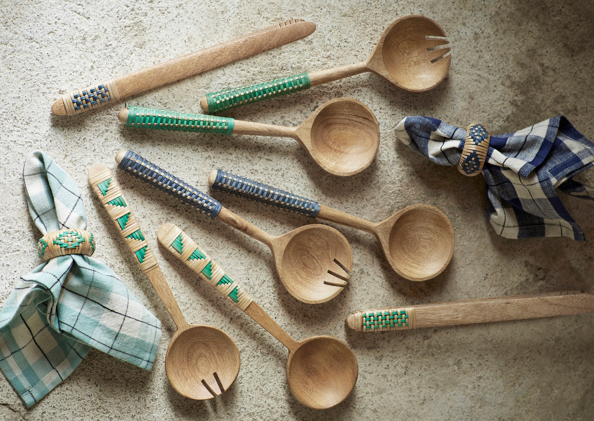 collection of wooden kitchen utensils with woven bamboo handles styled on a textured surface
