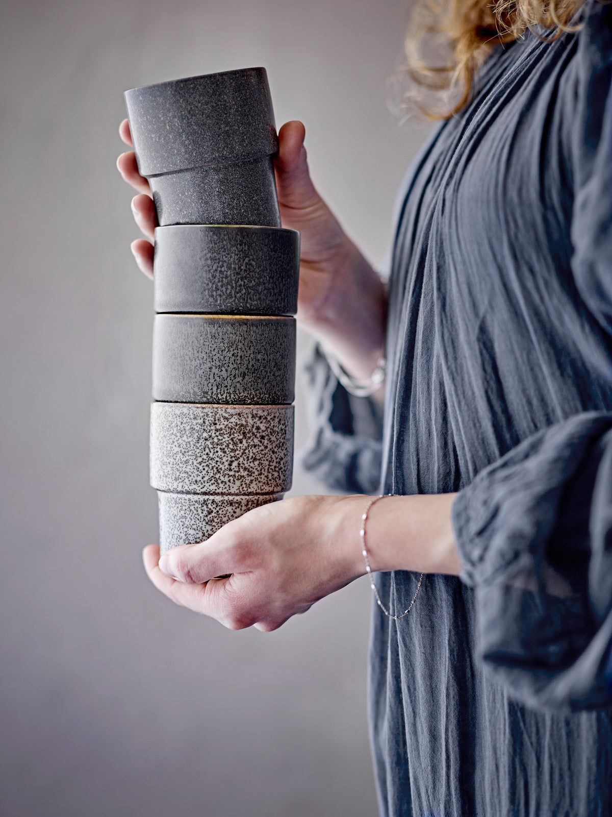 Stackable brown stoneware cups held in hand