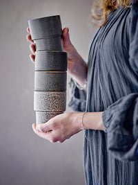 Stackable brown stoneware cups held in hand