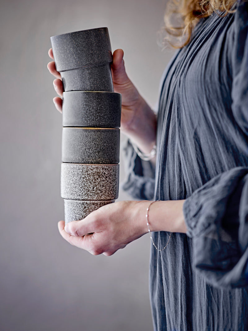 Stackable brown stoneware cups held in hand