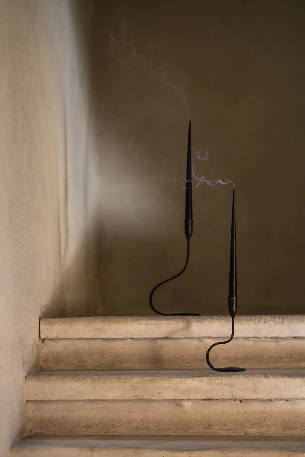 Two Steffi black cast iron taper candle holders by Olsson & Jensen styled on stone steps