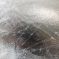 Close-up of crinkled metallic surface on silver faux leather cushion