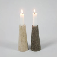 Light and dark travertine cone candle holders by Olsson & Jensen with lit candles
