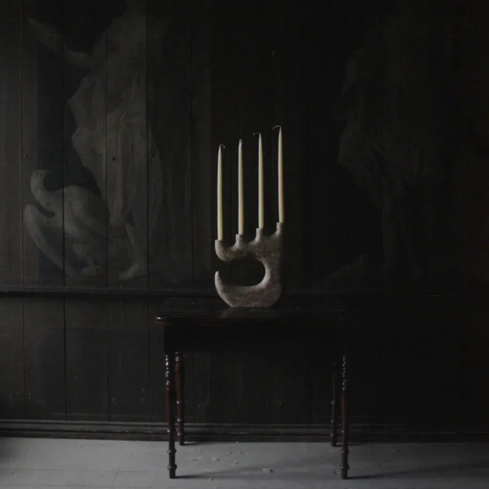 Travis four-arm candle holder by Olsson & Jensen with tall candles in a dark room