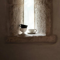 Tuva cup and saucer by Olsson & Jensen styled in a stone window