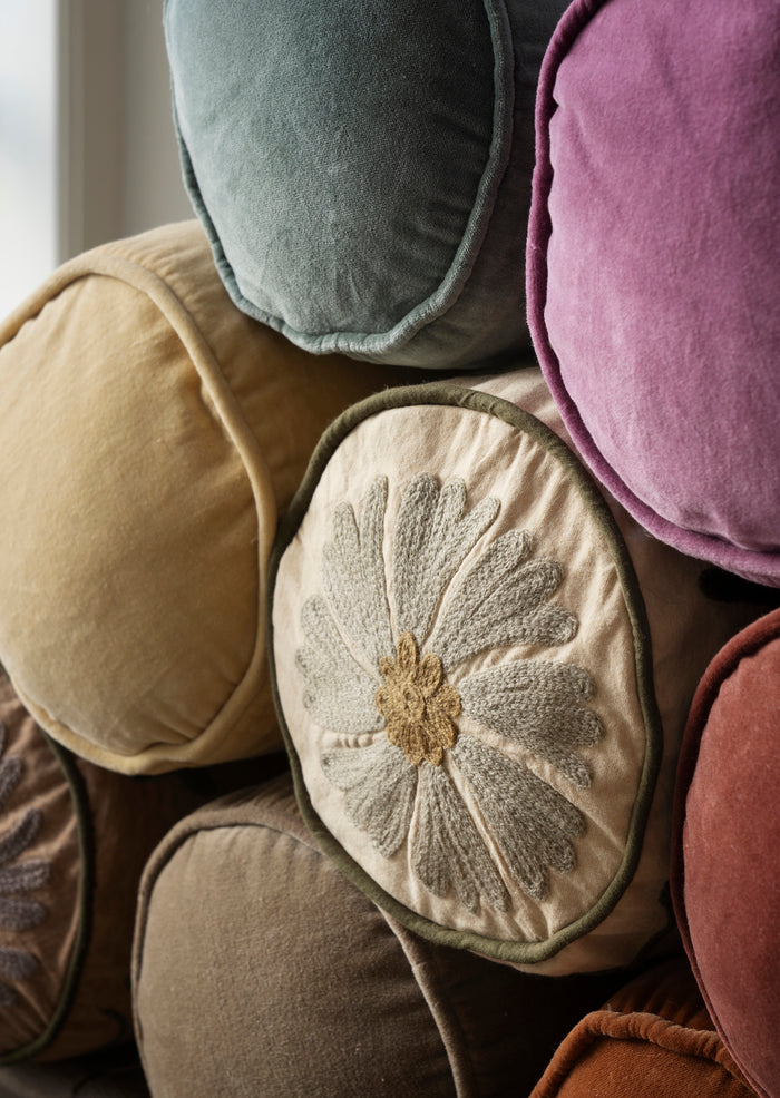 honey velvet bolster cushion stacked with round and colourful velvet cushions

