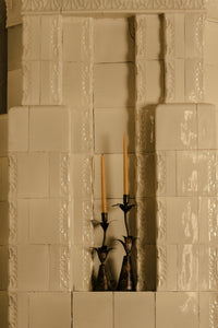 Vireo candlesticks by Olsson & Jensen with lit candles in a tiled stove alcove