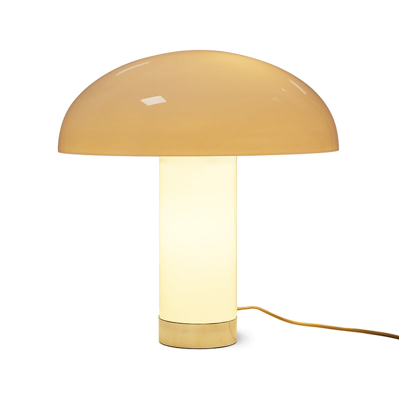 with the lights illuminating the base pedastal and the domed mushroom lamp shade giving it a warm yellow glow in the base and an almost beige light brown to the top. the hk living logo is barely visible with the lights gleaming through the reflective surfaces