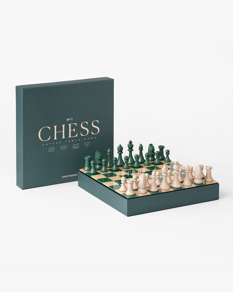Wooden chess pieces on green and cream board styled to look like coffee table book