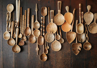 assorted handcrafted wooden kitchen utensils and salad servers styled on dark rustic wood