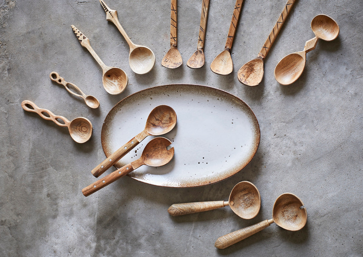 assorted handcrafted wooden spoons arranged around ceramic platter