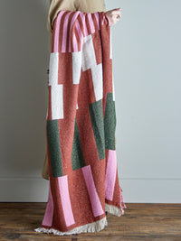 person holding recycled cotton york throw showing geometric pattern in red pink and green