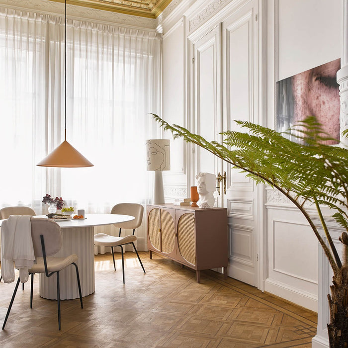 a dining room scene with a green fern on the foreground and hklivning lamps and crockery on the table