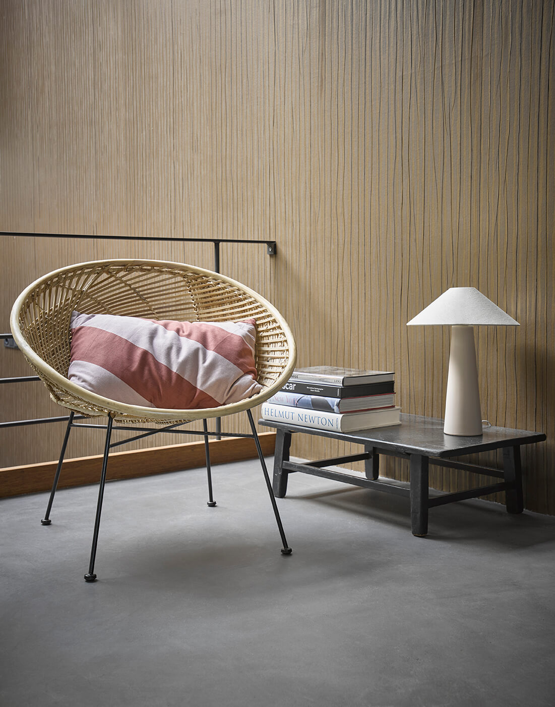 homescape with wicker bucket chair coffee table with books and a nude hkliving lamp with a classic sloped lamp shade