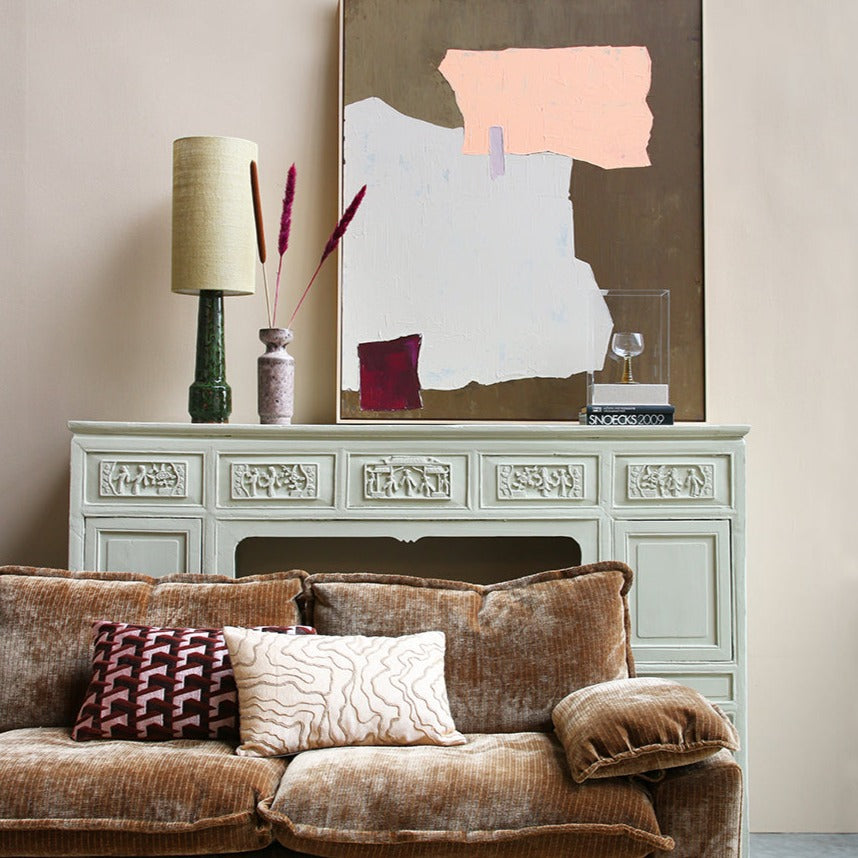 front room set-up with a brown velvet cordurouy sofa, fireplace behind, and on the fireplace a lamp from hkliving and other vases