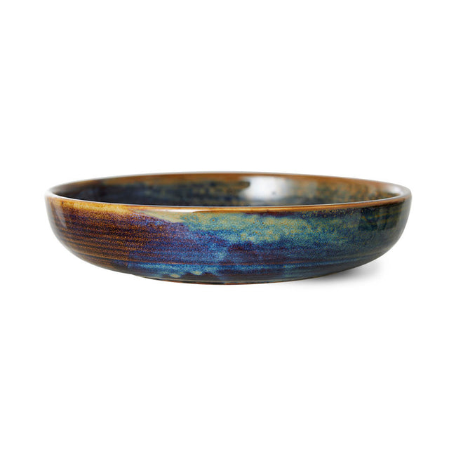 with a mix of coours from light and dark blue, freen, purple, browns, and golden hues: alomost looks like a deep space image covering this deep plate or pasta bowl from hkliving